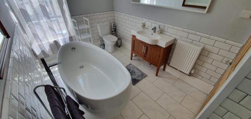 a white bathroom with a tub and a sink at Rocky Cove Bed and Breakfast in Ilfracombe