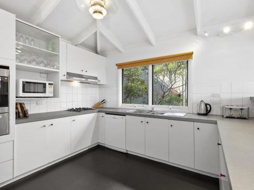 a white kitchen with white cabinets and a window at Niche On Noble in Anglesea