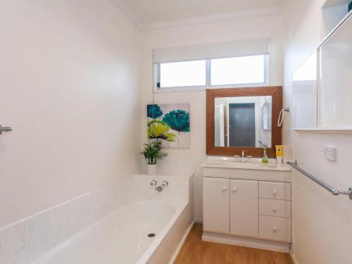 a white bathroom with a tub and a sink at Ocean Sounds in Anglesea