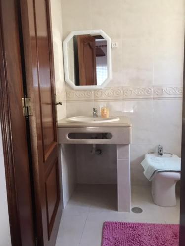 a bathroom with a sink and a mirror and a toilet at Vivenda Azevedo in Nazaré