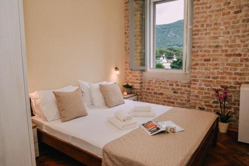 a bedroom with a white bed with a brick wall at Step to Kotor bay Guesthouse in Kotor