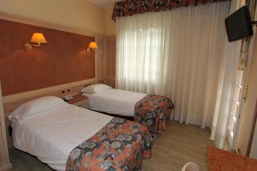 a hotel room with two beds and a television at Park Hotel in Reggio Emilia