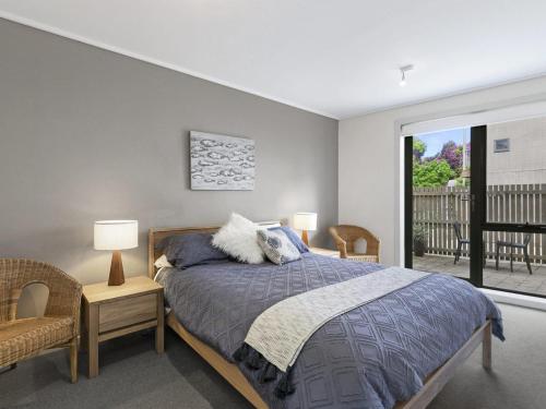 a bedroom with a bed and two chairs and a window at Apartment 23 Pacific Apartments in Lorne