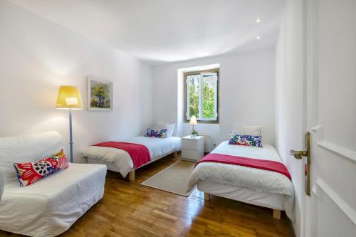 Habitación blanca con 2 camas y sofá en Vila Libania, en Queluz