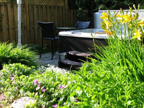a garden with a hot tub and some flowers at La Belle Victorienne in Magog-Orford