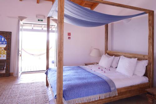 a bedroom with a canopy bed with a blue blanket at Monte Velho Retreat Centre in Aljezur