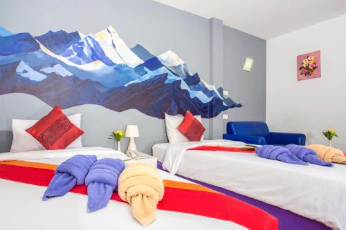 two beds in a room with a mountain mural on the wall at Le Nara Residence in Jomtien Beach