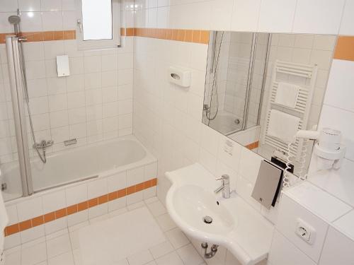a bathroom with a sink and a tub and a toilet at Hotel Goldener Adler in Linz