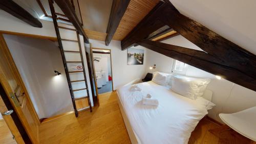 - une chambre avec un lit avec des draps blancs et une échelle dans l'établissement Spacious duplex city center Strasbourg, à Strasbourg