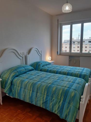 two beds in a bedroom with blue and yellow sheets at CASA CONTE in Pordenone