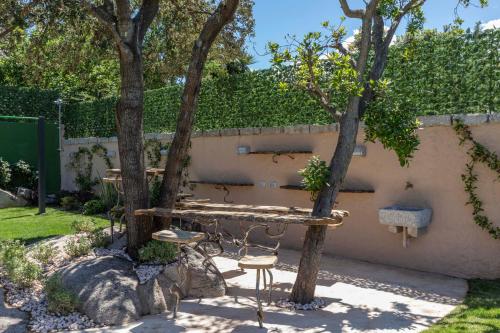 a table and chair in a garden with trees at Antica Fonte Holiday Homes in San Pantaleo