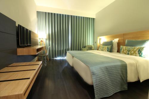 Habitación de hotel con cama grande y TV en Madeira Panorâmico Hotel, en Funchal