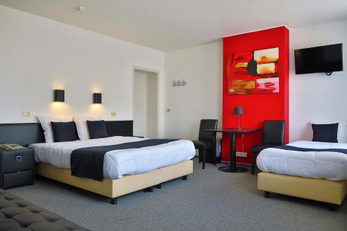 a hotel room with two beds and a red wall at Hotel Adoma in Ghent