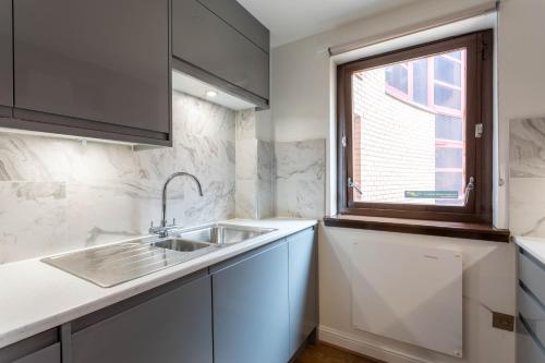 a kitchen with a sink and a window at Stunning 1 Bed Merchant City Apartment with Parking in Glasgow