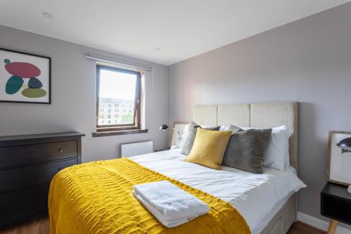 a bedroom with a large bed with a yellow blanket at Stunning 1 Bed Merchant City Apartment with Parking in Glasgow