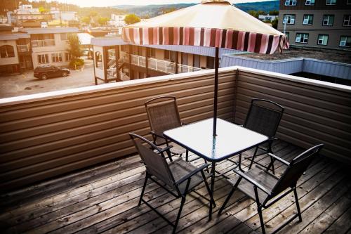 a table and chairs on a balcony with an umbrella at Ramada by Wyndham in Quesnel