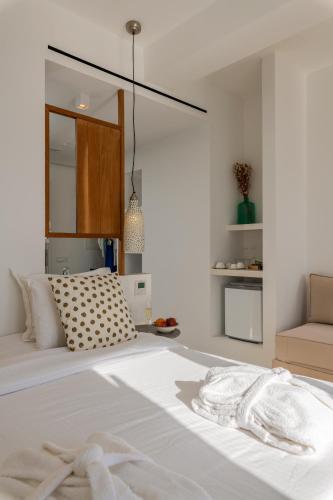 a bedroom with a large white bed with a mirror at Bluetopia Suites in Mýkonos City