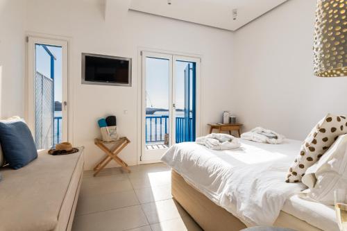 a white bedroom with a bed and a balcony at Bluetopia Suites in Mýkonos City
