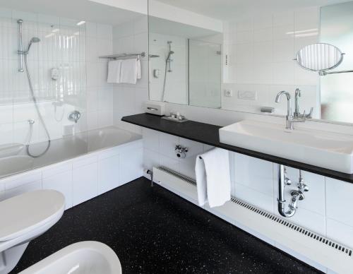 a white bathroom with a sink and a toilet at Parkhotel Hall in Tirol in Hall in Tirol