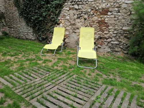 two yellow chairs sitting in the grass next to a wall at Petit studio hypercentre d'Orléans avec jardin in Orléans