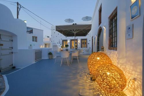 a patio with a table and chairs and lights at Radiant Santorini in Mesaria
