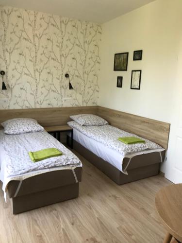 two beds in a room with a wooden floor at Kathia Pokoje Gościnne in Katowice