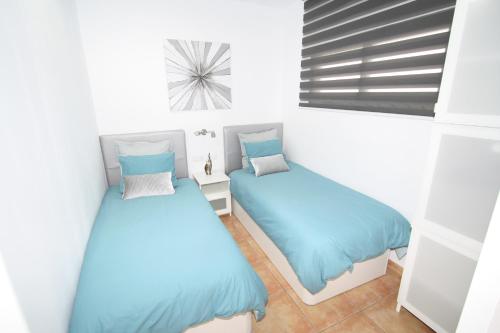 two beds in a room with blue sheets at Fantastic apartment near the beach in Playa del Ingles