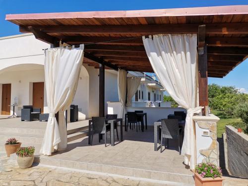 a wooden pergola with white curtains on a patio at Tenuta Turchi in Otranto