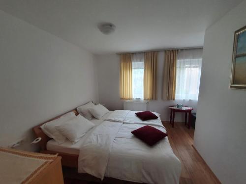 um quarto com uma cama com lençóis brancos e almofadas vermelhas em Apartma Meta em Radovljica