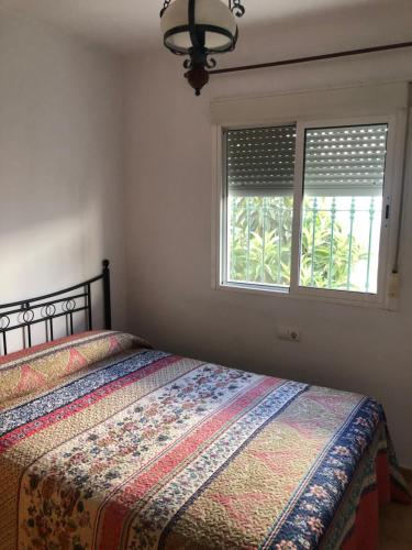 1 dormitorio con 1 cama y 2 ventanas en Casas Juani- chalet con piscina, en Conil de la Frontera