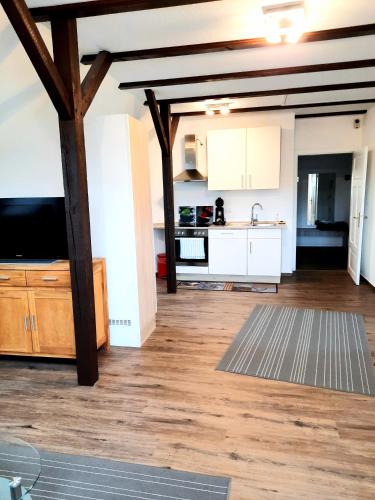 a kitchen with white cabinets and a tv in a room at Hotel Pellmühle in Jever