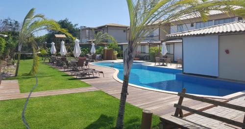 een resort met een zwembad en palmbomen bij Village Duplex Confortável e Acolhedor junto a Natureza in Itacimirim
