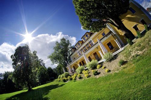 a large yellow building on a grassy hill with the sun at Kastiel Lucivna in Lučivná