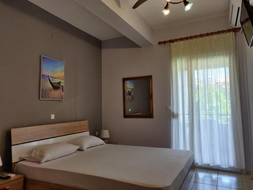 a bedroom with a large bed and a window at Methexis Apartment in Skala Potamias
