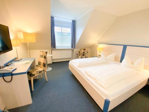 Schlafzimmer mit einem Bett, einem Schreibtisch und einem Computer in der Unterkunft Hotel Wikingerhof in Kropp