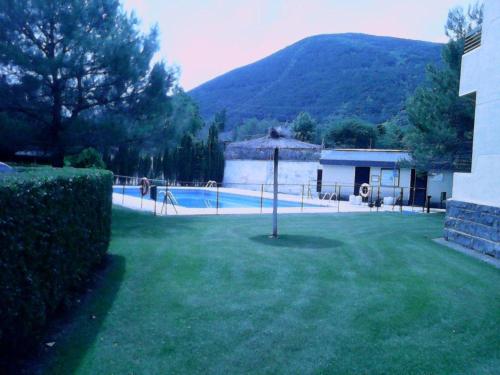 a yard with a swimming pool with a house and a mountain at apartamento Valles Blancos 3-6 in Biescas