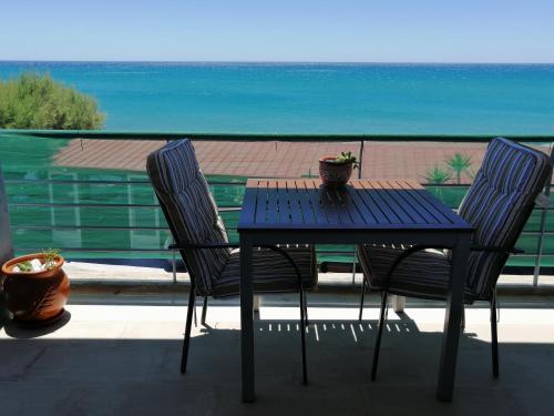 a table and two chairs on a balcony with the ocean at Jason Rooms & Studios in Keratokampos