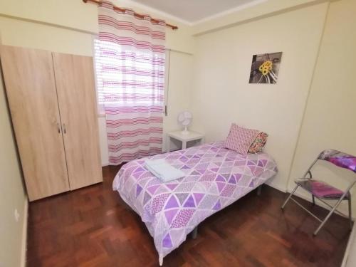 Un pequeño dormitorio con una cama púrpura y una silla en Apartamento Penha T3, en Faro