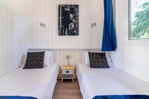 2 Betten in einem Zimmer mit weißen Wänden und blauen Vorhängen in der Unterkunft Les minis homes du Bugey - Eco-lodge City, un refuge en hyper centre in Ambérieu-en-Bugey