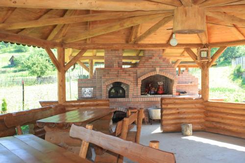 a wooden pavilion with a table and a brick oven at Pensiunea Paradiso in Poiana Teiului