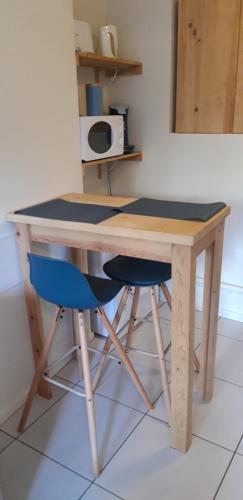 une table en bois avec une chaise bleue et un bureau dans l'établissement studio avec terrasse et jardinet en centre ville, à Bergerac