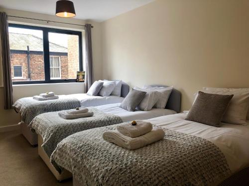a room with three beds with towels on them at Vikings Two Bedroom Apartment With Free Parking. in York