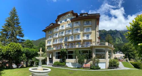 a large building with a fountain in front of it at Hotel Regina in Wengen