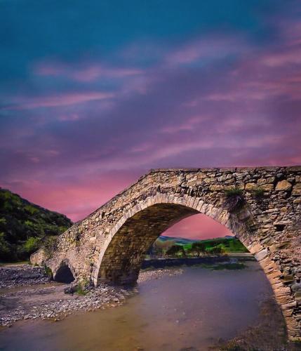 a stone bridge over a river with a purple sky at B&B al centro storico in Troina