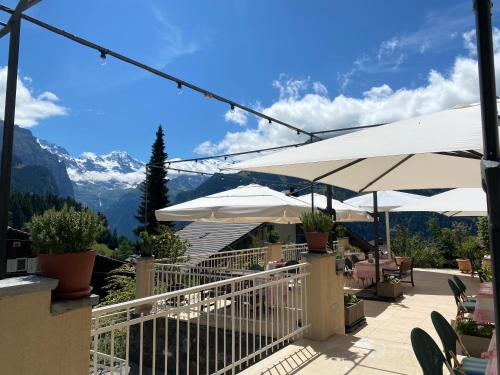 a patio with white umbrellas and a view of mountains at Hotel Regina in Wengen
