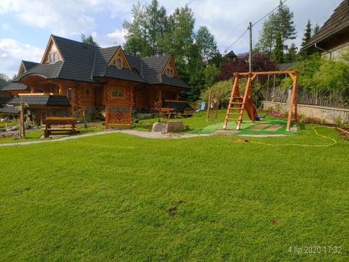 una casa de madera con parque infantil en el patio en Przystań w Tatrach - Przytulne Domki i Apartamenty-Luxury Chalets and Apartments, en Bukowina Tatrzańska