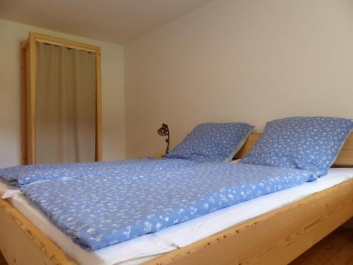 Una cama con almohadas azules encima. en Haus Schritte, en Hinterweiler