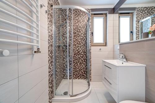 La salle de bains est pourvue d'une douche et d'un lavabo. dans l'établissement White Apartment Swinemünde, à Świnoujście