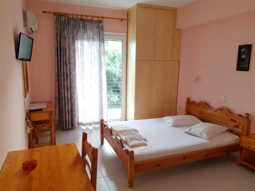 a bedroom with a bed and a table and a window at STUDIOS LEFTERIS in Nydri
