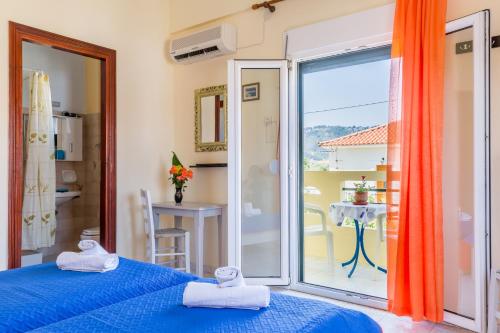 a bedroom with a blue bed and a balcony at Pension Soula in Skopelos Town